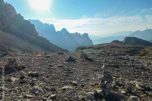 A field filled with stone men. In the back there are high chains of Italian Dolomites, shrouded in morning haze. The whole area is full of lose stones. Raw and desolated landscape. Solitude photo