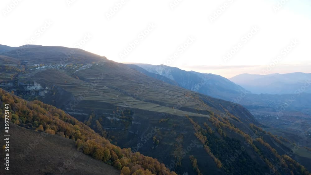 Wonderful large valley with ancient mountains covered with autumn forest and green fields under clear sky in evening panoramic view Wonderful large valley with ancient mountains covered with autumn forest and green fields under clear sky in evening panoramic view