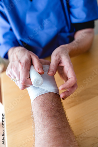 Close-up of female nurse bandaging a hand or arm home care
