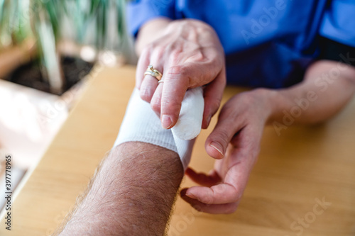 Close-up of female nurse bandaging a hand or arm home care