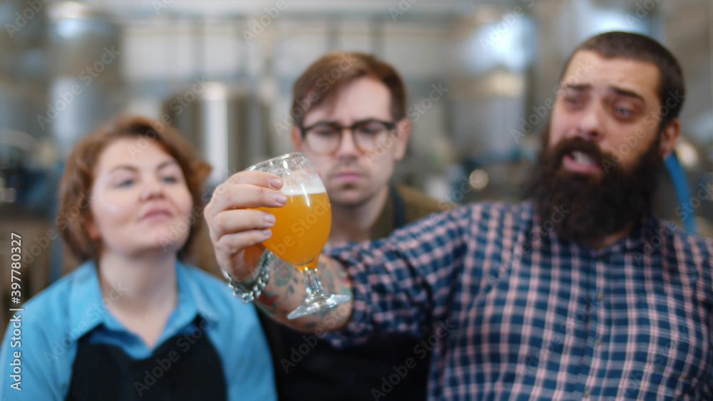 Specialist standing with glasses of beer explaining brewing process to visitors