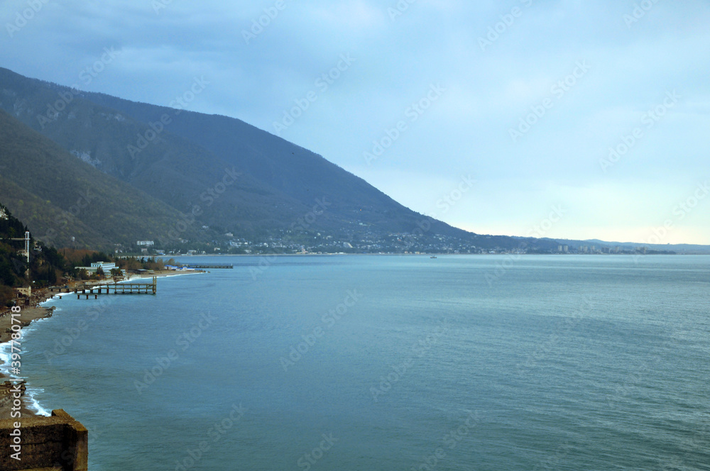 Coast of the Black Sea, the mountains in blue haze in the background. Autumn season in Sochi, Krasnodarsky Krai, Russia. Coast of the Black Sea, the mountains in blue haze in the background. Autumn season in Sochi, Krasnodarsky Krai, Russia.