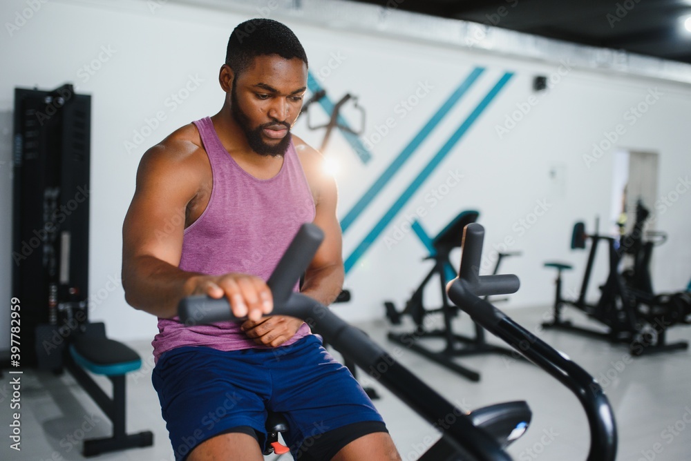 african man using stationary bicycle in a gym african man using stationary bicycle in a gym