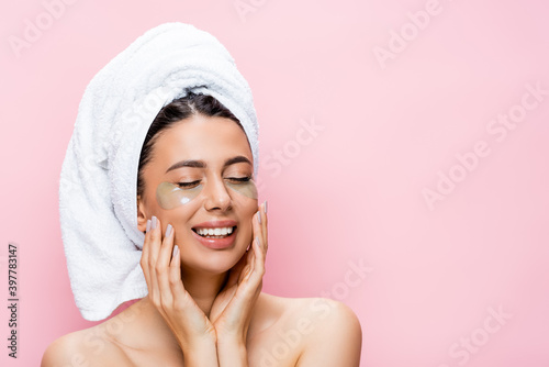 smiling beautiful woman with towel on hair and hydrogel eye patches on face isolated on pink