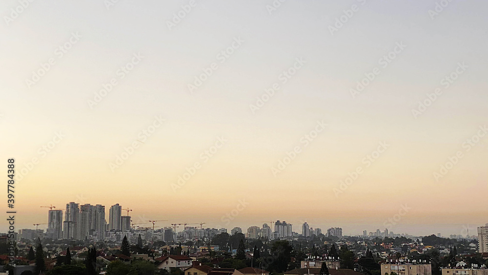 Obraz premium The roofs of city buildings against the background of the sunset