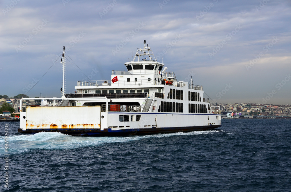 Ferry goes to European side from Asian side of Istanbul under clear sky, full of vehicles.  This is the alternative way for drivers instead of using bridges. Also Galata Tower is visible as background