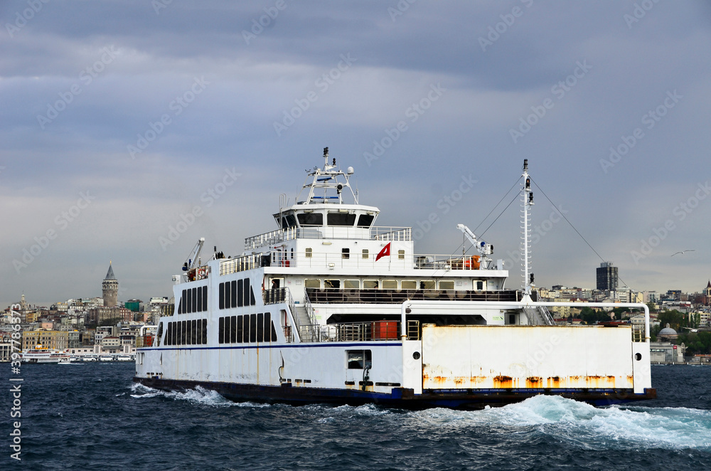 Ferry goes to European side from Asian side of Istanbul under clear sky, full of vehicles.  This is the alternative way for drivers instead of using bridges. Also Galata Tower is visible as background