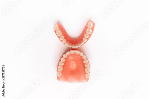 Full removable plastic denture of the jaws. Set of dentures on a white background. Two acrylic dentures. Upper and lower jaws with fake teeth. Dentures or false teeth, close-up. Copy space