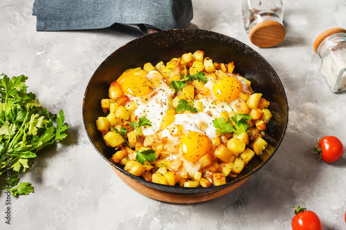 Potato hash with eggs and herbs for breakfast on concrete background