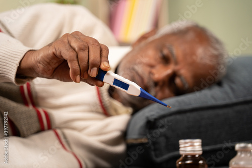Selective focus on thermometer, sick bed ridden old man seeing temperature on thermometer.