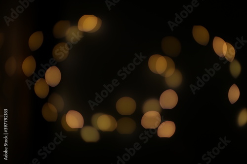 Background of golden, yellow bokeh (led strip light in a 50mm lens) on a dark black background. Design elements
