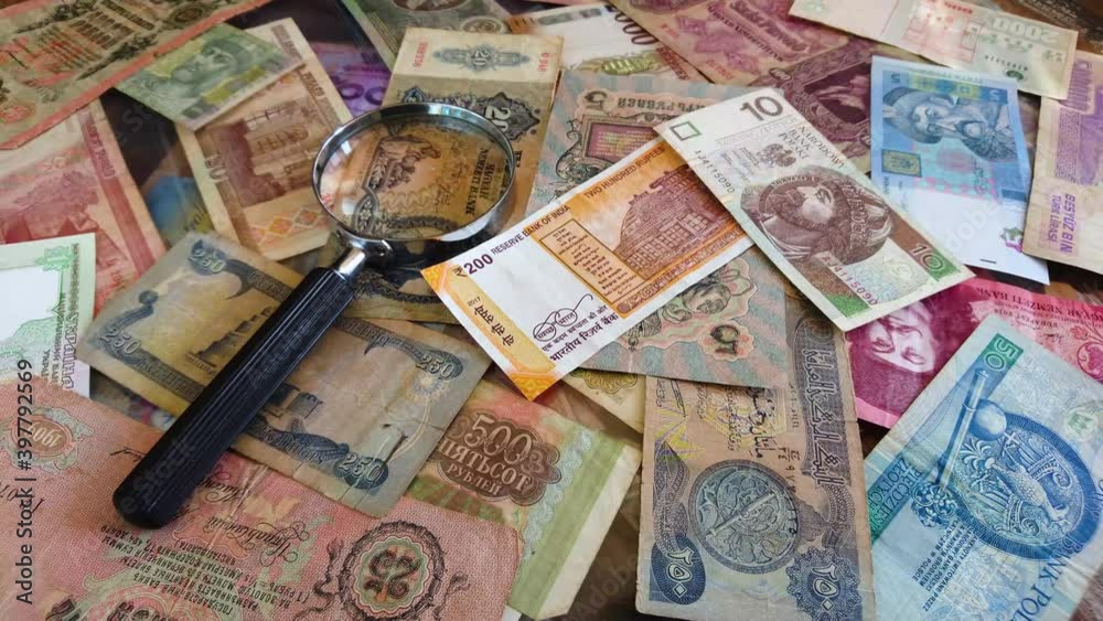 Background from different collector banknotes with a magnifying glass, top view Background from different collector banknotes with a magnifying glass, top view