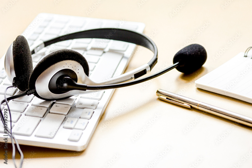 Office desk with headset and keyboard brown background Office desk with headset and keyboard brown background