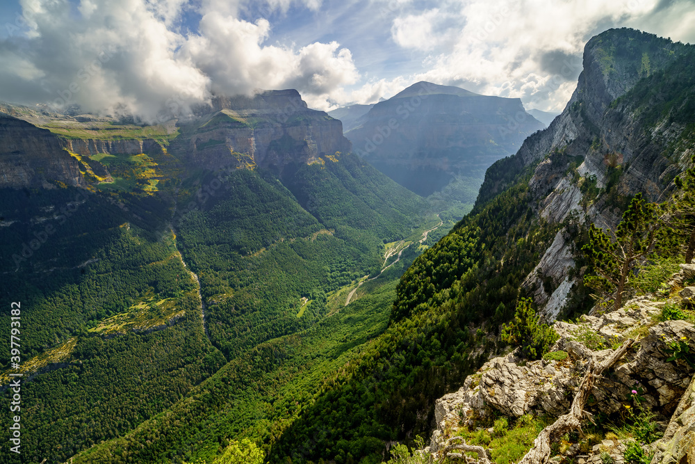 Green landscape in the Pyrenees of the Ordesa and Monte Perdido valley with mountains, rocks, forests and sky with clouds. Top aerial view.
