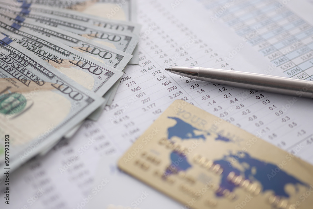 Bank credit card and dollars lying on table with numbers closeup Bank credit card and dollars lying on table with numbers closeup