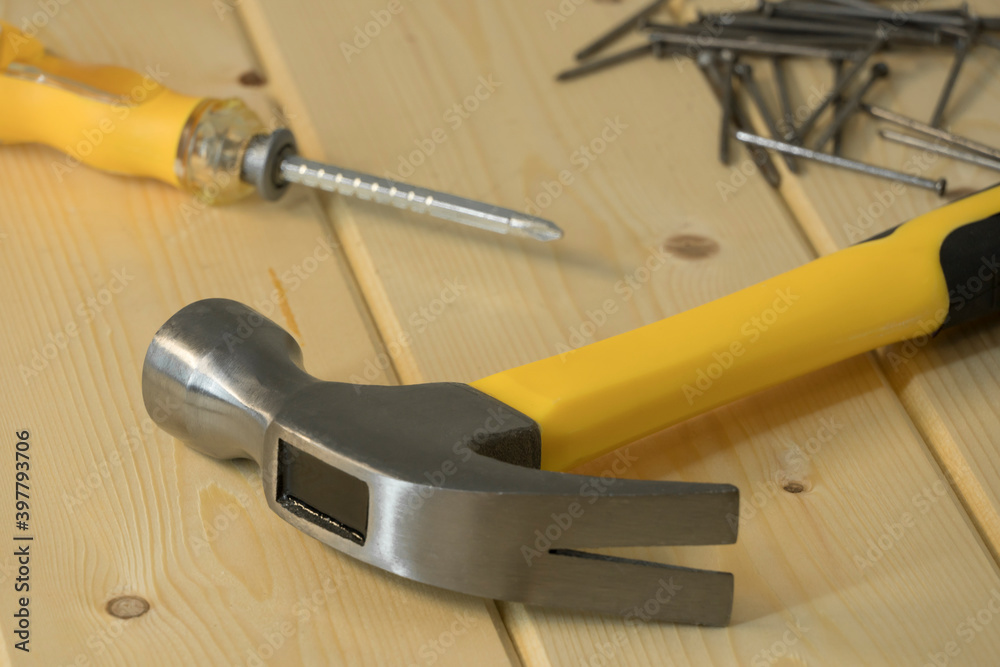 Assorted work tools on wood. Hand tools on a wooden background, hammer with nails and screwdriver. Home renovation, construction. Hand tools and equipment. An assortment of tools. Assorted work tools on wood. Hand tools on a wooden background, hammer with nails and screwdriver. Home renovation, construction. Hand tools and equipment. An assortment of tools.