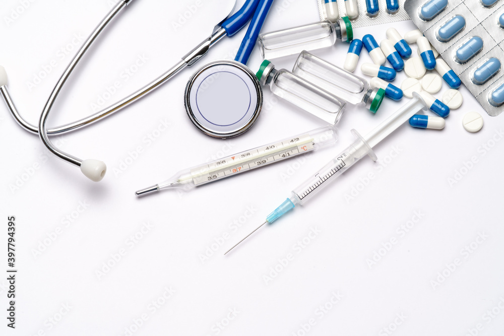 stethoscope, thermometer, syringe and capsules pills over light grey or white background - top view flat layout stethoscope, thermometer, syringe and capsules pills over light grey or white background - top view flat layout