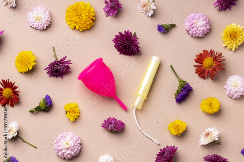 Fototapeta Naklejka Na Ścianę i Meble -  Menstrual cup and tampons on floral pattern background