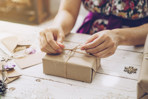 Woman hand making beautiful Christmas gift box at table