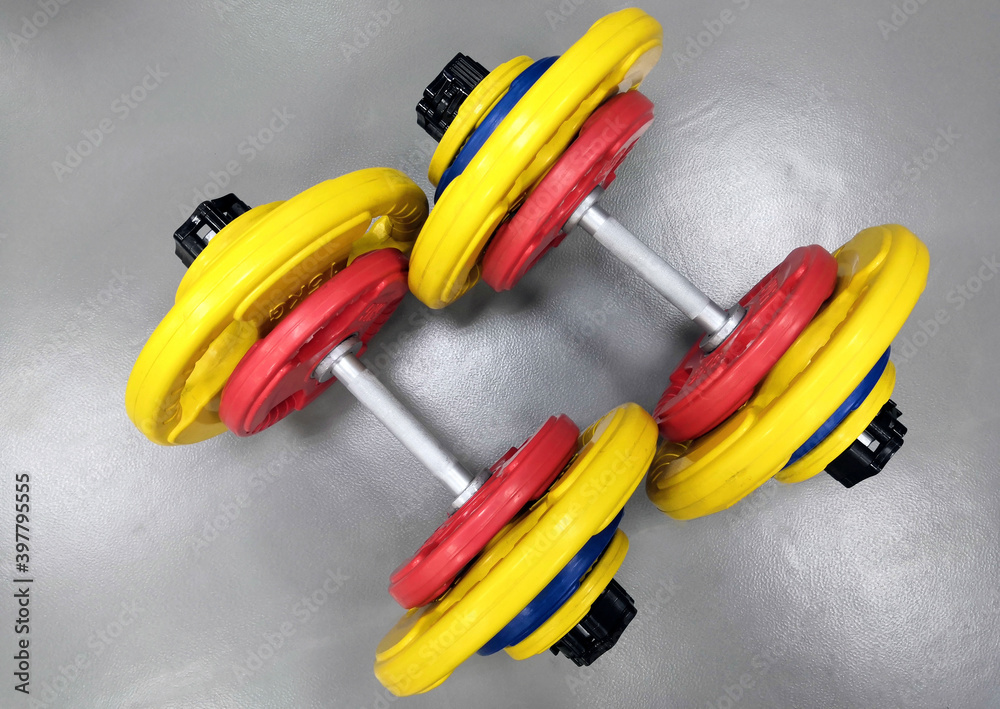 Prefabricated sports dumbbells on a gray background with multi-colored discs put on