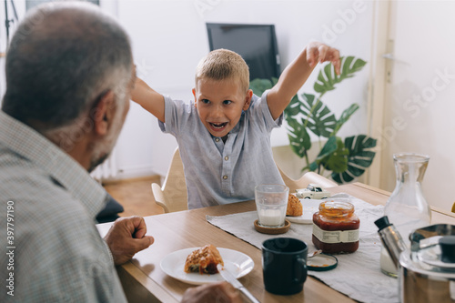 grandfather and his grandson having breakfast at home