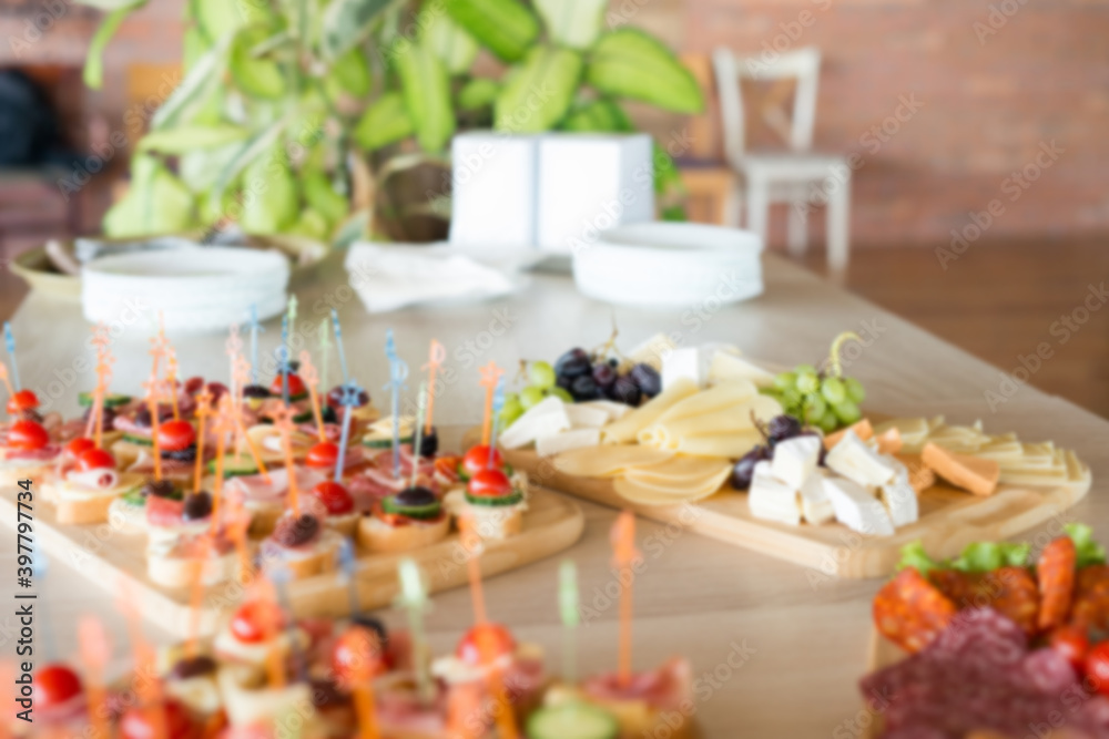 The buffet at the reception. Assortment of canapes on wooden board. Banquet service. Catering, snacks with different types of cheese and meat. Party Concept.