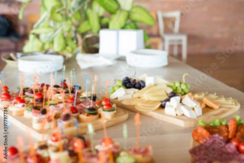 The buffet at the reception. Assortment of canapes on wooden board. Banquet service. Catering, snacks with different types of cheese and meat. Party Concept.