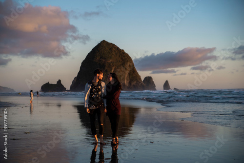 young couple walking along canon beach in oregon