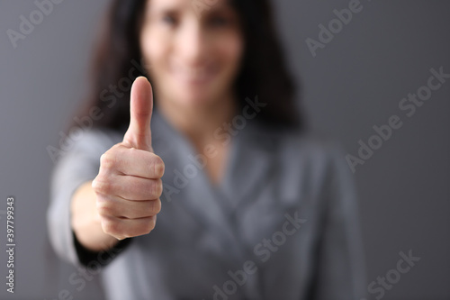 Modern business woman showing thumb up in office closeup