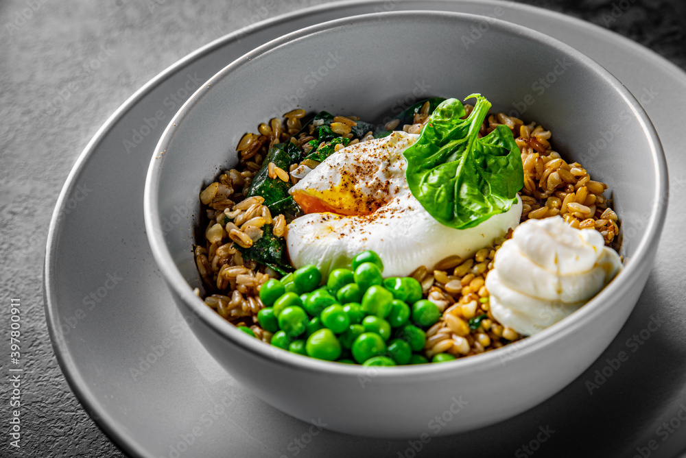 alted oatmeal with poached egg and green pea in a bowl on Dark grey black slate background
