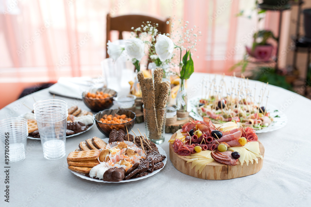 The buffet at the reception. Assortment of canapes on a table. Banquet service. Catering food, snacks with different types of cheese, ham, salami, prosciutto, shrimp, vegetables and fruits. 