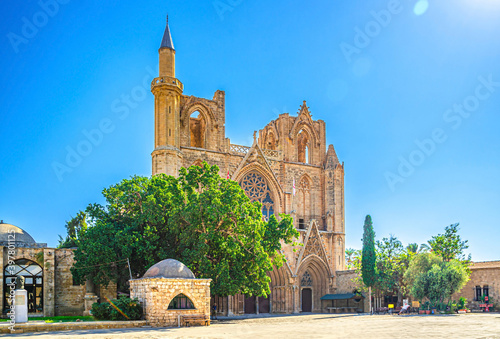 Lala Mustafa Pasha Camii Mosque or Old Cathedral of Saint Nicholas medieval building with minaret in Famagusta historical city centre, clear blue sky in sunny day, Cyprus