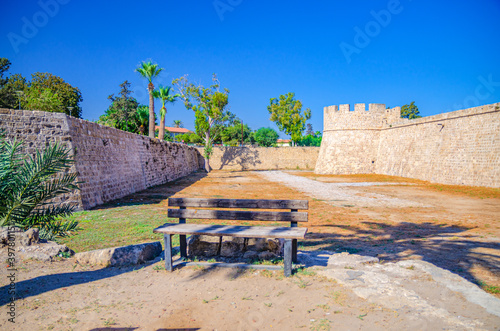 Othello Castle or Othello's Tower medieval building and wooden bench in Famagusta historical city centre, clear blue sky in sunny day, Cyprus photo