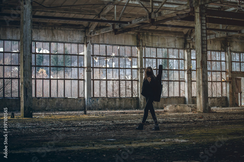 young tall girl with a guitar walks through an abandoned room