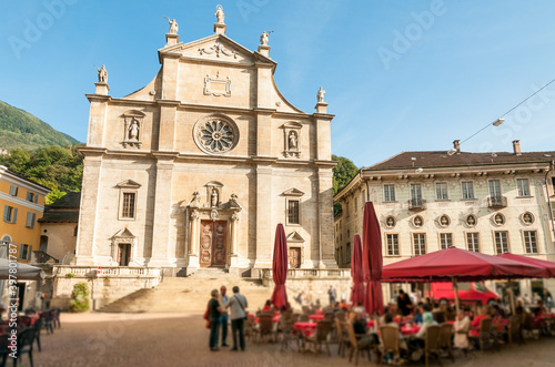a, Ticino, Switzerland - 25 September 2014: Collegiate Church of Saints Peter and Stephen, with outdoor restaurant in front in the historic center of Bellinzona, Switzerland
