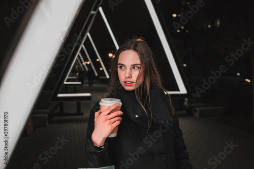 girl in winter atmosphere in lights in the evening with coff