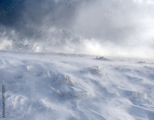 A mountain slope covered with a layer of snow during strong winds. Trapped in motion.