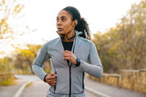 African american sportswoman using earphones while running in park