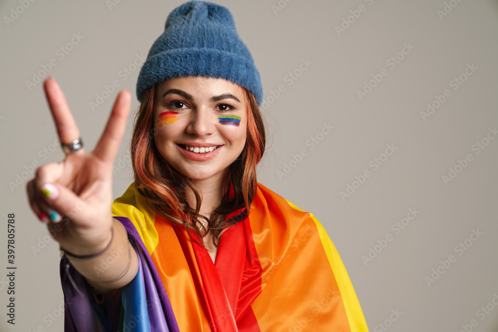 Cheerful woman wearing rainbow flag showing peace sign Cheerful woman wearing rainbow flag showing peace sign