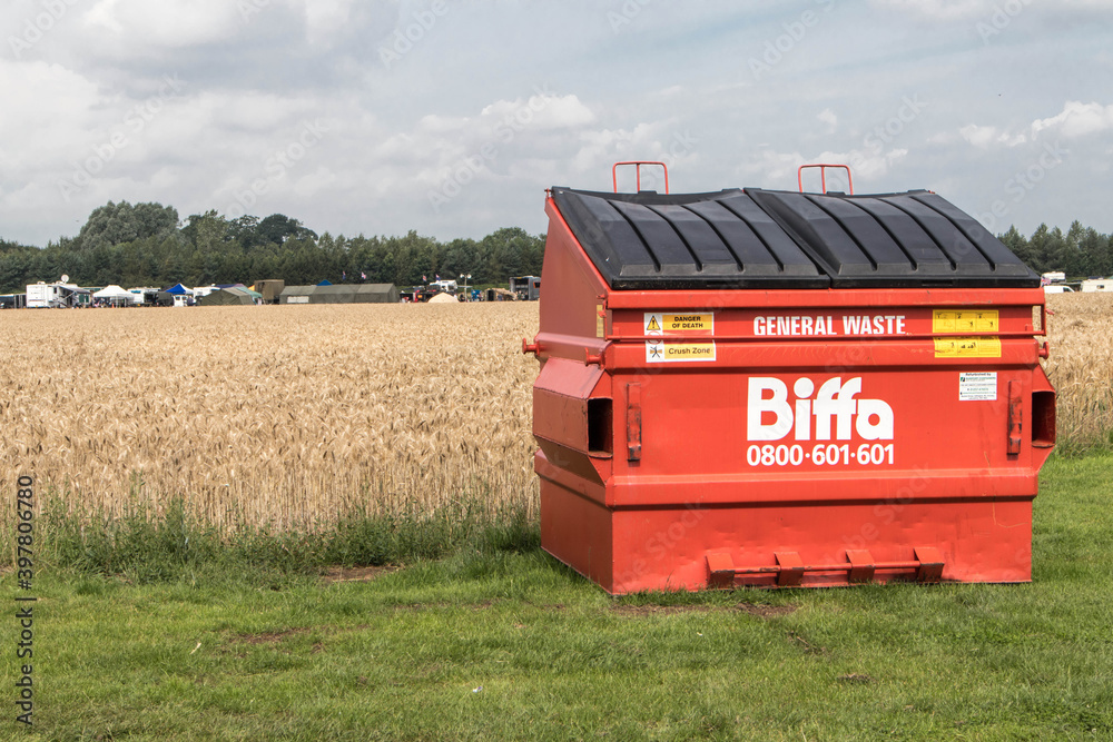 Large red Biffa General Waste container garbage rubish bin in a field