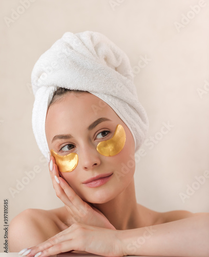 Young beautiful woman with silicone gold eye patches. Facial care at home. Girl with clean skin. Young beautiful girl cares for the skin using patches under the eyes at home.