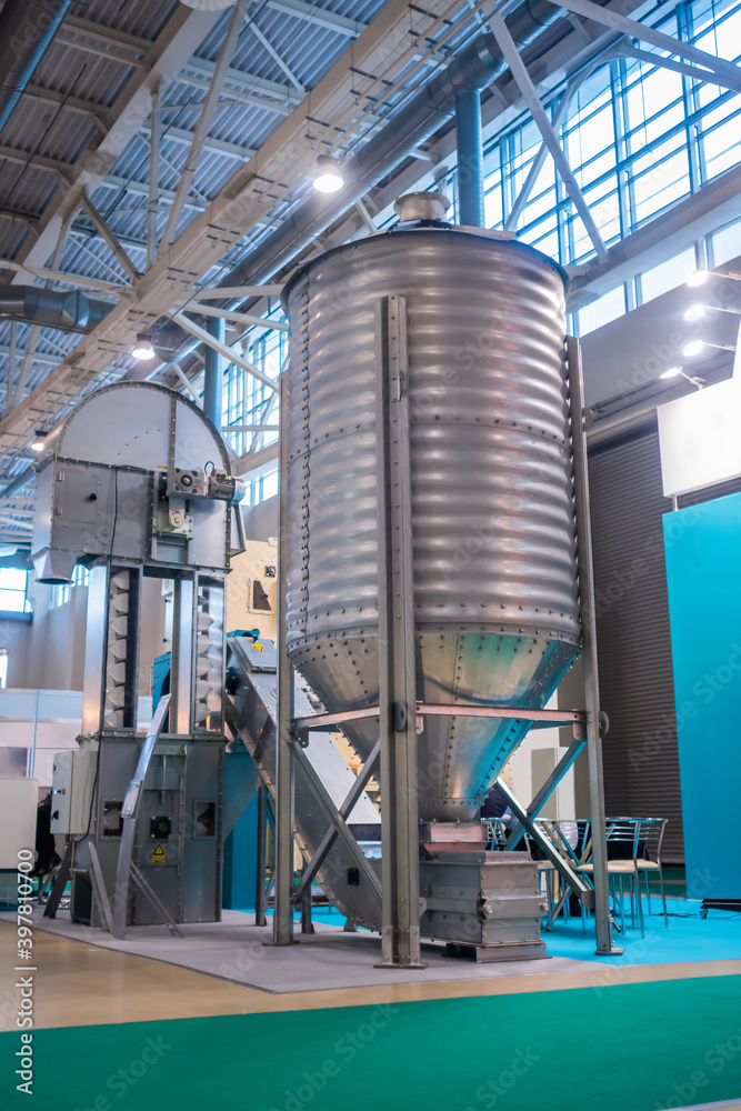 Grain store silo with discharge hopper - storage of agricultural food production at farming exhibition, trade show. Agriculture industry and automated technology equipment concept Grain store silo with discharge hopper - storage of agricultural food production at farming exhibition, trade show. Agriculture industry and automated technology equipment concept