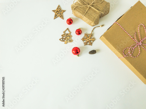 Christmas present boxes with wooden christmas ornaments, christmas ball ornaments and a pine cone on an isolated white surface, top view