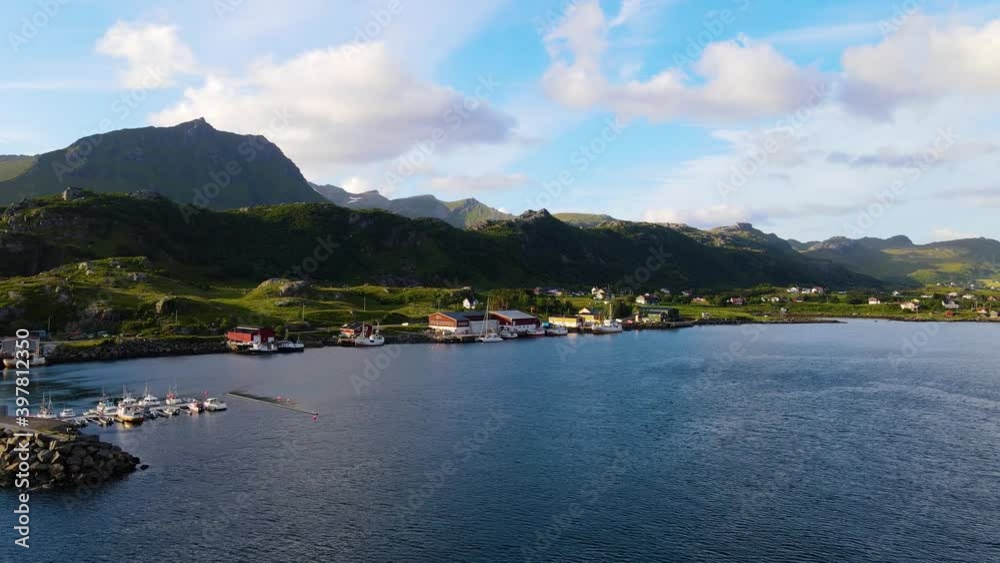 Aerial, drone view over a pier towards a yacht, anchored, in a small town, sunny day, in Lofoten, Norway Aerial, drone view over a pier towards a yacht, anchored, in a small town, sunny day, in Lofoten, Norway
