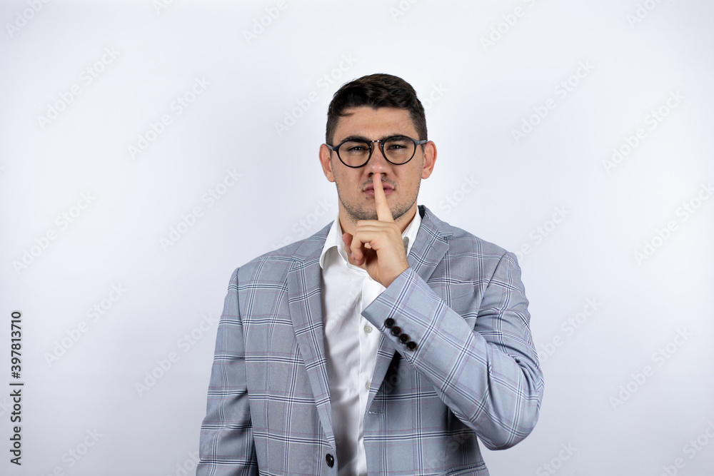 Business young man wearing a casual shirt over white background asking to be quiet with finger on lips. Silence and secret concept. Business young man wearing a casual shirt over white background asking to be quiet with finger on lips. Silence and secret concept.