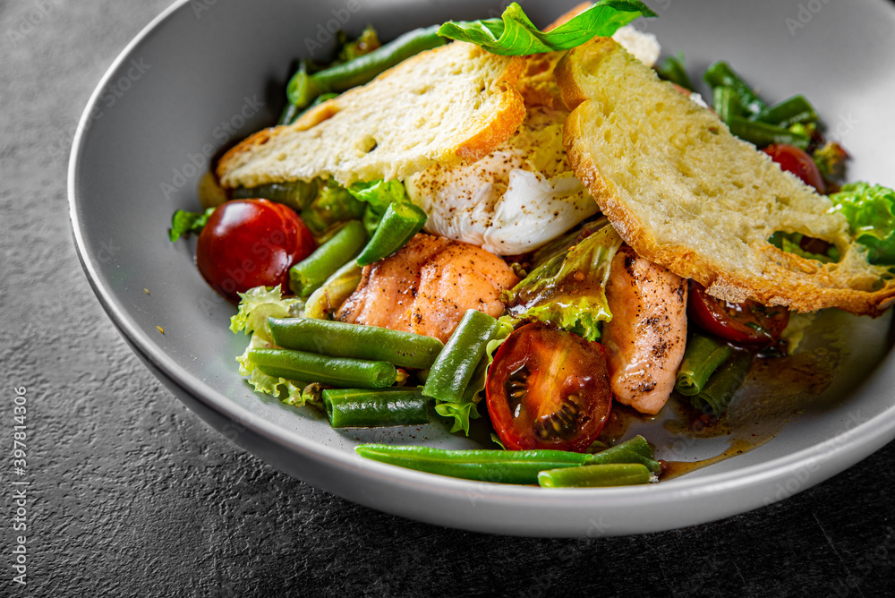 Green Bean Salad with Boiled Eggs, Salmon, Tomatoes and Arugula in a bowl on Dark grey black slate background Green Bean Salad with Boiled Eggs, Salmon, Tomatoes and Arugula in a bowl on Dark grey black slate background