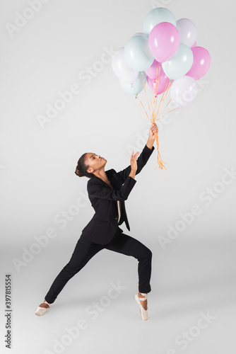 african american businesswoman performing ballet with balloons isolated on grey