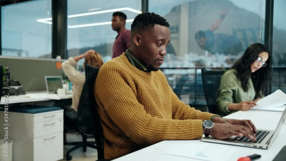 African American male working on laptop typing fast emails working with colleagues in office 