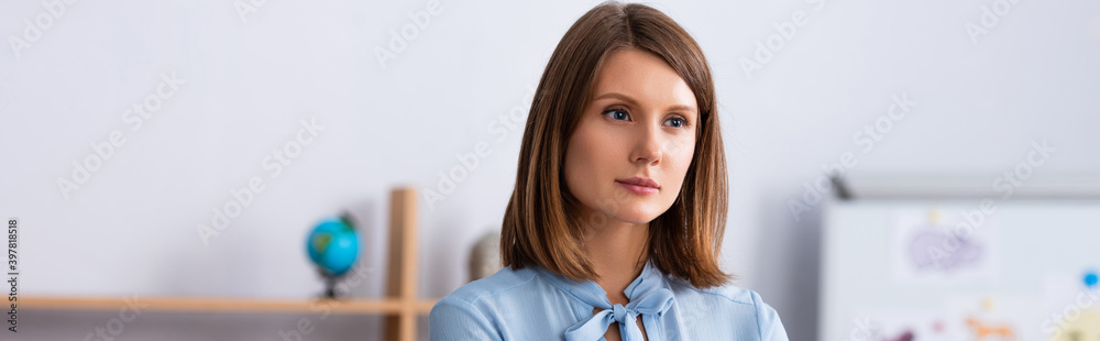 Portrait of thoughtful female psychologist looking away on blurred background, banner