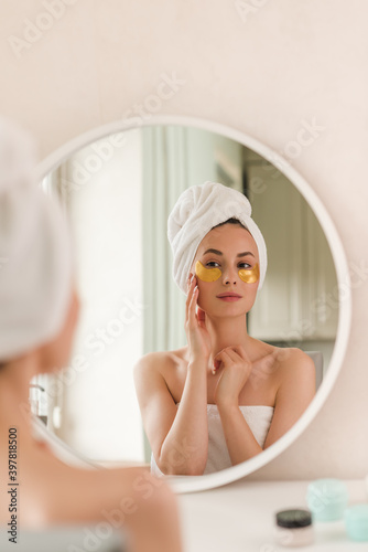 Young beautiful woman with silicone gold eye patches. Facial care at home. Girl with clean skin. Young beautiful girl cares for the skin using patches under the eyes at home.